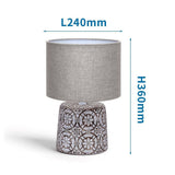 Dekorative Tischlampe aus Keramik mit Ornamenten und rundem Stoffschirm.