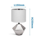 Edle silberfarbene Tischlampe aus Keramik mit 6-eckigem Fuss und weißem Stoffschirm.